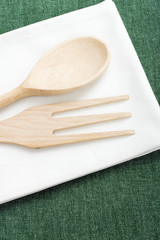 wooden spoon and fork placed on a white napkin.