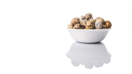 Quail eggs in white bowl over white background