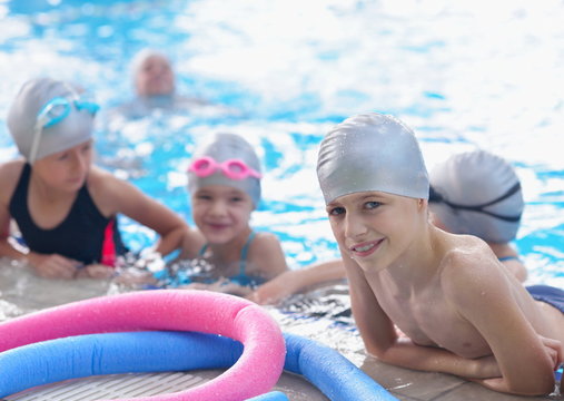 group of happy kids children at swimming pool class learning to 
