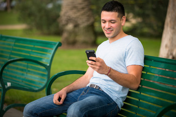 Young guy using his phone at the park