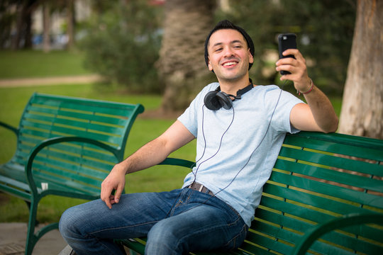Young hip male taking a selfie at the park