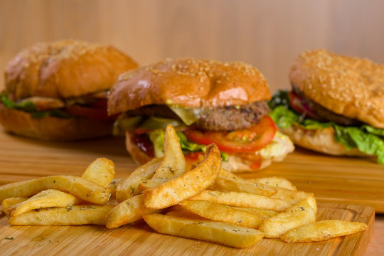 Potatoes fries with tasty fresh burgers standing on wooden board