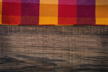 Fototapeta premium Top view of checkered napkin on empty wooden table