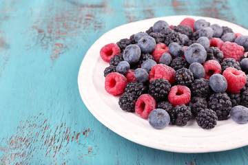 Iced berries on plate, on color wooden background