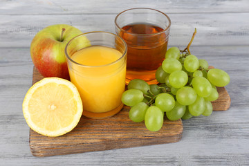 glasses of juice with fresh fruits on grey wooden table