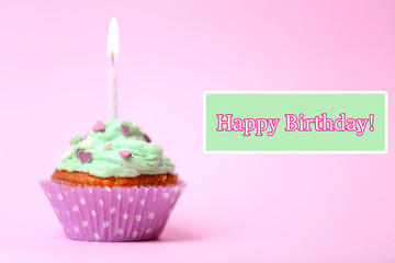 Delicious birthday cupcake on table on pink background