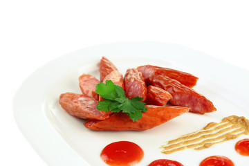 Smoked thin sausages and vegetables on plate, isolated on white