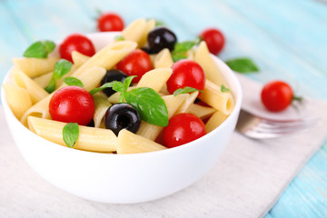 Fototapeta na wymiar Pasta with tomatoes, olives and basil leaves in bowl