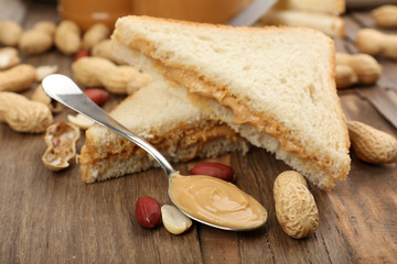 Bread slices with creamy peanut butter on wooden table