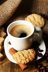 Cup of espresso and tasty cookie on wooden background