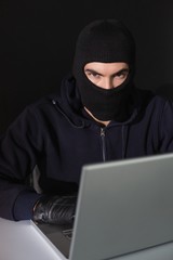Burglar sitting hacking laptop while looking at camera