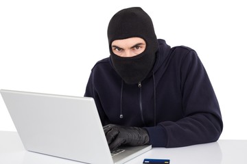 Hacker in balaclava hacking a laptop