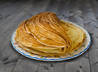 a pile of pancakes on the plate on the old wooden table
