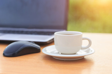 Close up coffee cup and laptop on the table in the morning