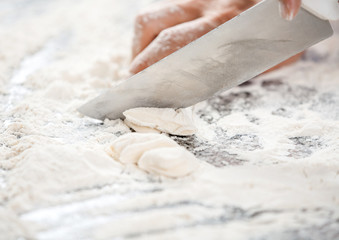 Chef's Hand Cutting Dough At Messy Counter