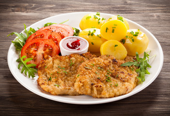 Fried pork chop, boiled potatoes and vegetable salad