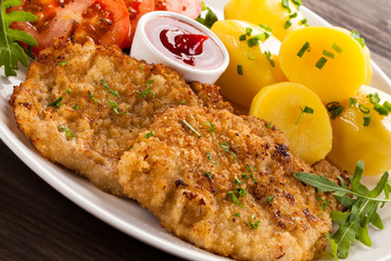 Fried pork chop, boiled potatoes and vegetable salad