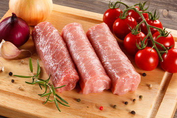Raw pork chops on cutting board and vegetables