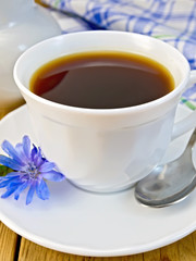 Chicory drink in white cup with milkman and flower on board