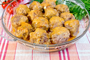 Meatballs with sauce in glass pan on linen tablecloth