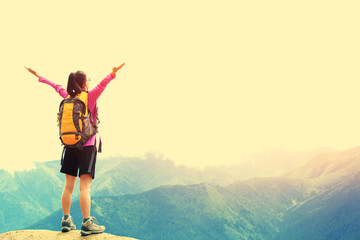 Fototapeta na wymiar cheering woman hiker open arms at mountain peak 