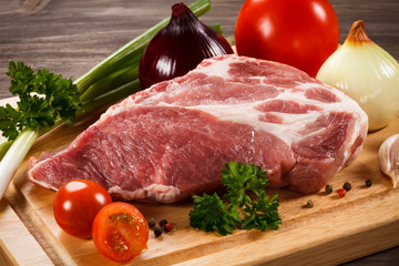 Raw pork on cutting board and vegetables