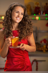 Portrait of happy young woman drinking tea in christmas kitchen