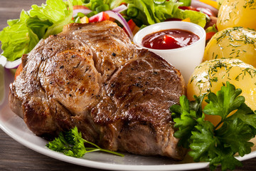 Barbecued steak, boiled potatoes and vegetable salad