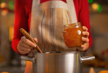 Closeup on young housewife making orange jam