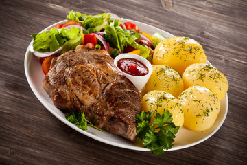 Barbecued steak, boiled potatoes and vegetable salad