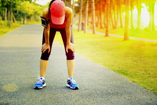 Tired Female Runner Taking A Rest After Running At Tropical Park