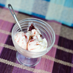 Glass bowl of icecream with raspberry topping