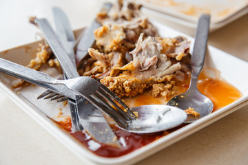 Plate with remnants of fried chicken in the restaurant