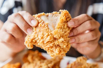 Abwaschbare Fototapete Hand holding Fried chicken and eating in the restaurant © SKT Studio