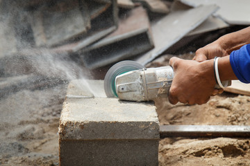 Hand holding angle grinder to cut the brick