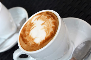Cup of hot cappuccino on the black background
