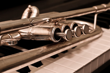 Detail of trumpet lying on the piano keys