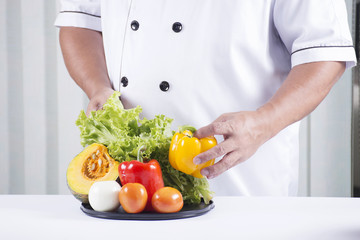 cook holds tray of vegetable