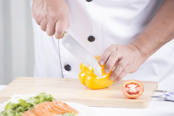 Chef's hands cutting yellow bell pepper
