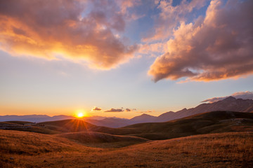 Tramonto tra le montagne e nuvole tinte di rosa