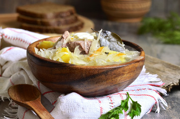 Rustic sour cabbage soup with goose in a wooden bowl.