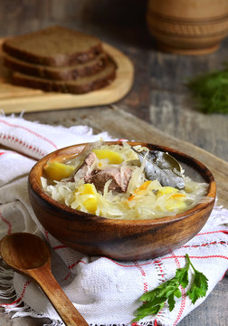 Rustic sour cabbage soup with goose in a wooden bowl.