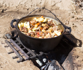 meat with potatoes in a cauldron on fire