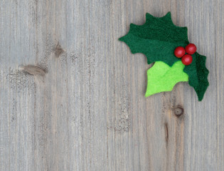 Christmas holly with red berries isolated on a wood background
