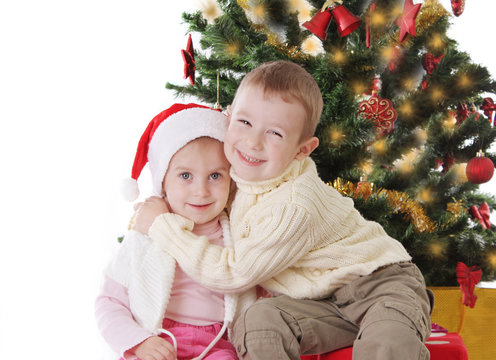 Sister and brother hugging under Christmas tree