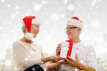 happy senior couple in santa hats with gift box