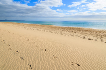 Fototapeta na wymiar Footprints in sand on Morro Jable beach, Fuerteventura island