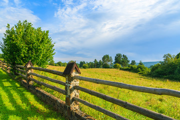 Wooden fence on green field in Bieszczady Mountains, Poland