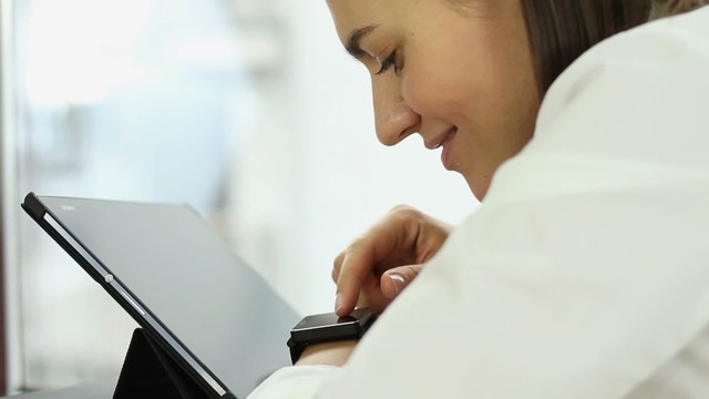 Happy woman using tablet computer and smart watch in the office