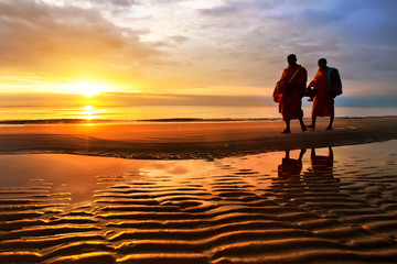 Silhouettes of monks on Hua Hin beach Thailand